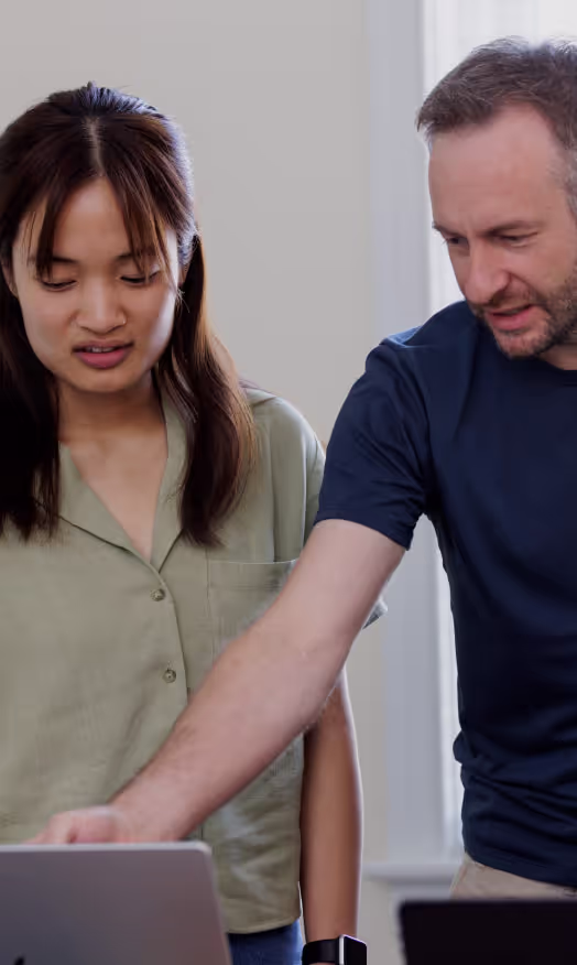Two team members reviewing code on a laptop